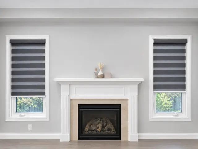 Charcoal zebra blinds on two windows either side of a fireplace