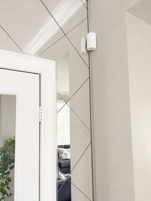 Alarm door sensor installed on a white entry door frame